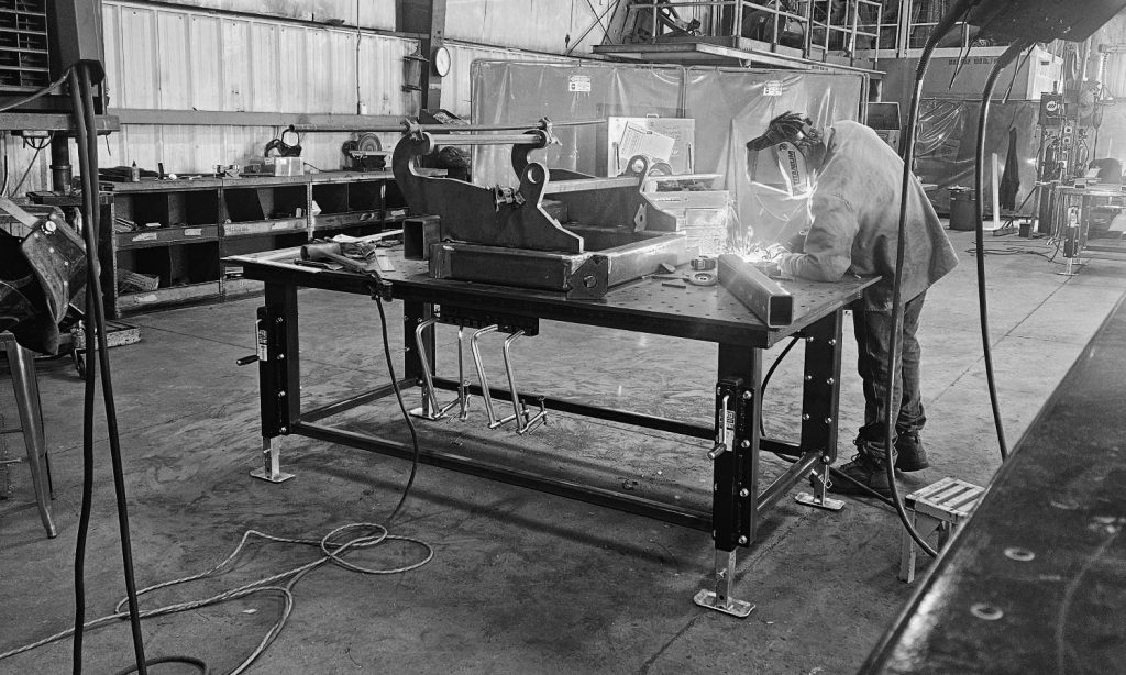 Team member welding a frame kit component at Bish Enterprises’ workshop